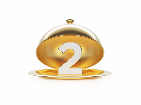 Number 2 sitting inside of a gold platter sitting on white background. Horizontal composition with copy space.