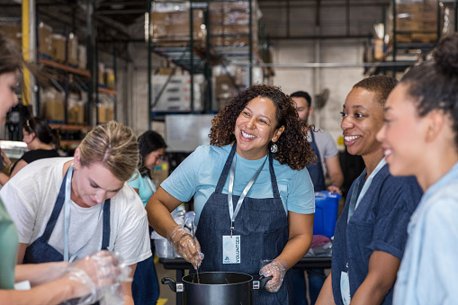 A diverse group of women smile and talk as they prepare food to serve at the soup kitchen.