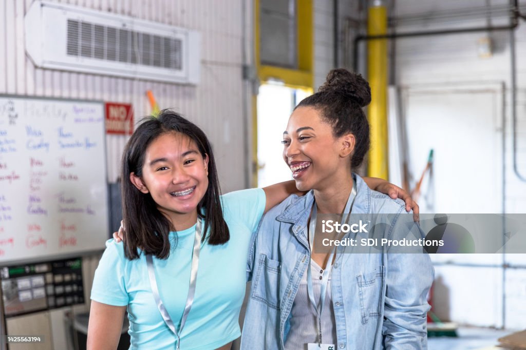 While volunteering, sisters stand with arms around each other When they volunteer at the community event, the sisters smile and stand with their arms around each other. Homelessness Stock Photo