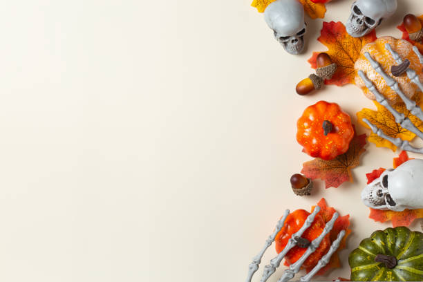 Halloween greeting card with pumpkin, skulls, bony hands and leaves