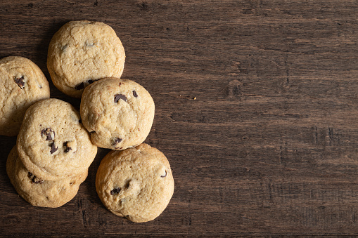 Border of fresh home made chocolate chip cookies on a dark wood background with copy space