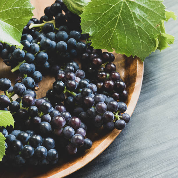 istock Bunches of dark grapes on teak tray 1425569160
