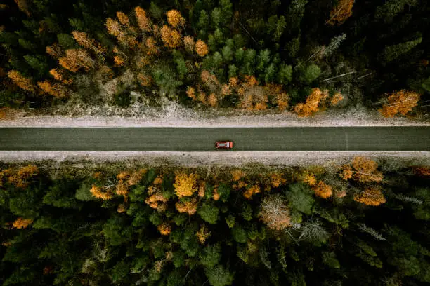 Photo of Aerial view of fall road with autumn woods and first snow in Finland.