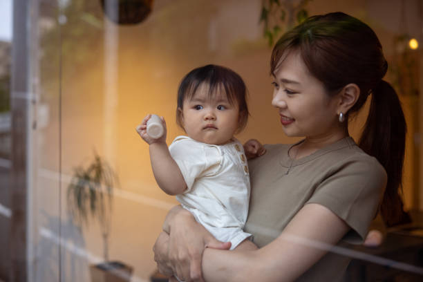 Mother holding daughter nearby the window Woman staying at home and taking medicine setagaya ward stock pictures, royalty-free photos & images