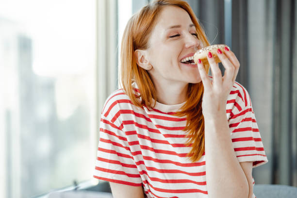 retrato de una hermosa mujer disfrutando comiendo un donut - tasting women eating expressing positivity fotografías e imágenes de stock
