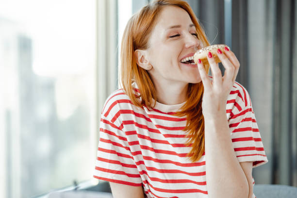 ドーナツを食べて楽しむ美しい女性の肖像画 - tasting women eating expressing positivity ストックフォトと画像