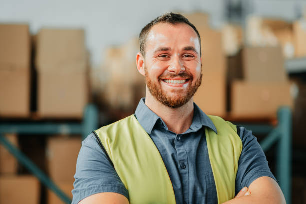 factory or warehouse worker in shipping plant happy and smiling about new import and export cargo. portrait of a young logistics or supply chain industry manager looking excited and proud - warehouse worker imagens e fotografias de stock