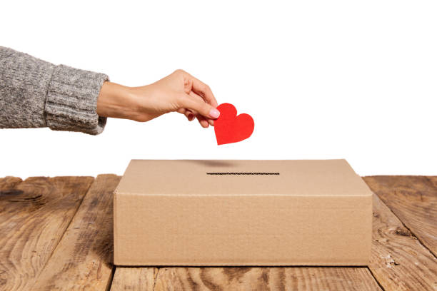 Charity. Red heart as symbol of peace, love is putting by female hand into slot of donation carton box. Concept of donorship, life saving or charity Charity. Red heart as symbol of peace, love is putting by female hand into slot of donation carton box. Concept of donorship, life saving or charity. Concept of help, health, social issues donation box stock pictures, royalty-free photos & images