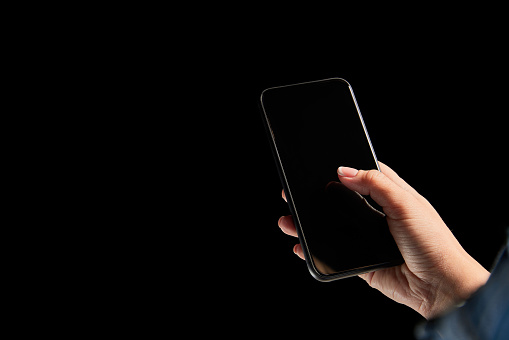 Female hands scrolling phone screen, using gadget for donation isolated on dark background. Concept of modern technologies, networking, gadgets. Copy space for ad, text