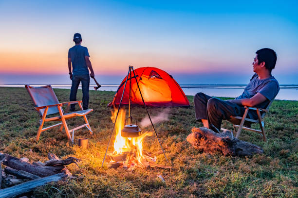 istock Two people camping by the lake with a bonfire 1425583344
