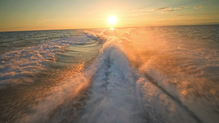 Yacht leaving a wake behind as the sun is setting