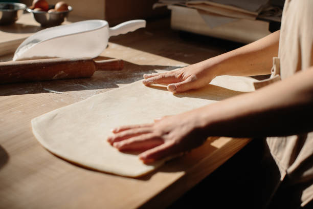 istock Woman hands rolling out dough in flour with rolling pin in bakery. 1425585331