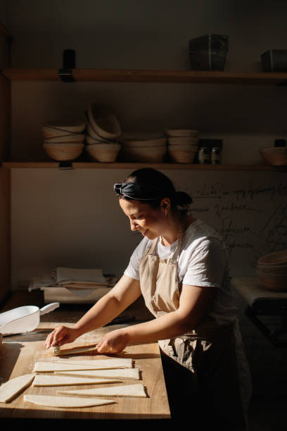 istock Female baker rolls the dough into rolls, the process of baking a croissant. Selected focus, bakery concept 1425585410