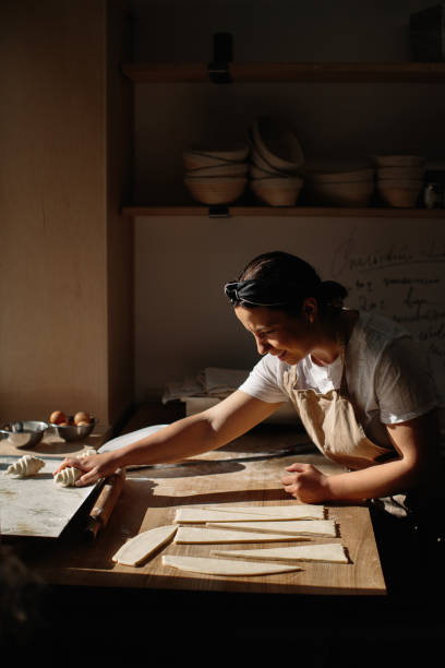 istock Female baker rolls the dough into rolls, the process of baking a croissant. Selected focus, bakery concept 1425585429