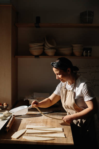 istock Female baker rolls the dough into rolls, the process of baking a croissant. Selected focus, bakery concept 1425585435