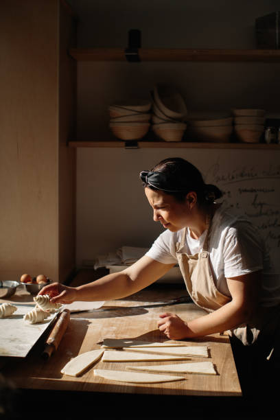 istock Female baker rolls the dough into rolls, the process of baking a croissant. Selected focus, bakery concept 1425585451