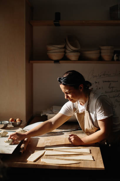 istock Female baker rolls the dough into rolls, the process of baking a croissant. Selected focus, bakery concept 1425585455