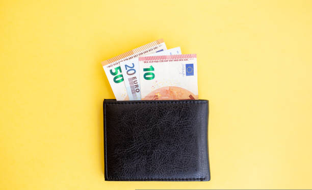 istock Different euro banknotes inside a black wallet on yellow background 1425585494