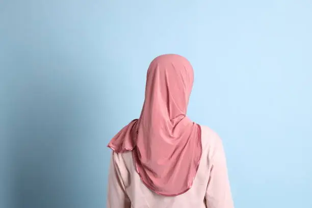 The senior southeast Asian woman with hijab standing on the blue background