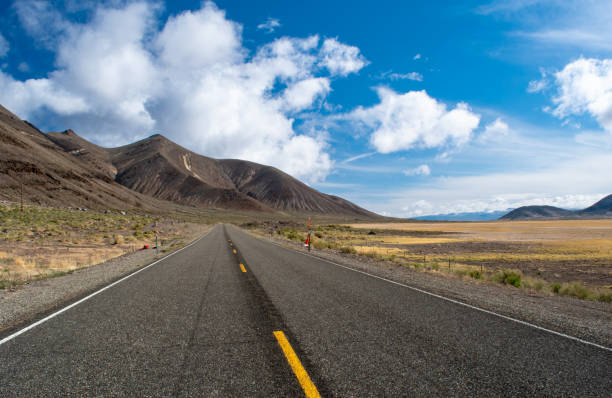 istock Desolate highway going off into the horizon in the high desert with fluffy clouds. 1425594057