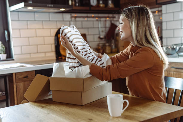 istock Young woman opening package and holding ordered item 1425594123