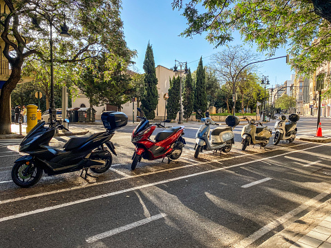 Valencia, Spain - May 7, 2022: Many motor scooters parked in a row in dedicated space for them. There use became so widespread that the city government created legal places to park them