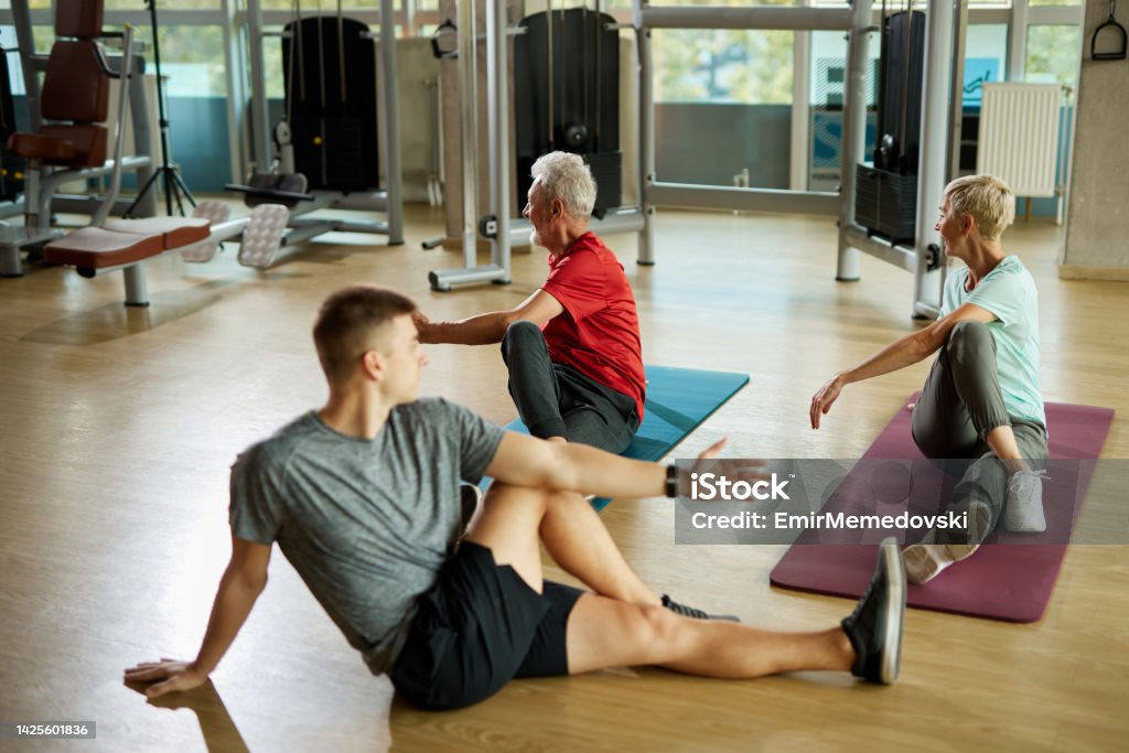 Senior couple doing stretching exercises with personal trainer at the gym A Helping Hand Stock Photo