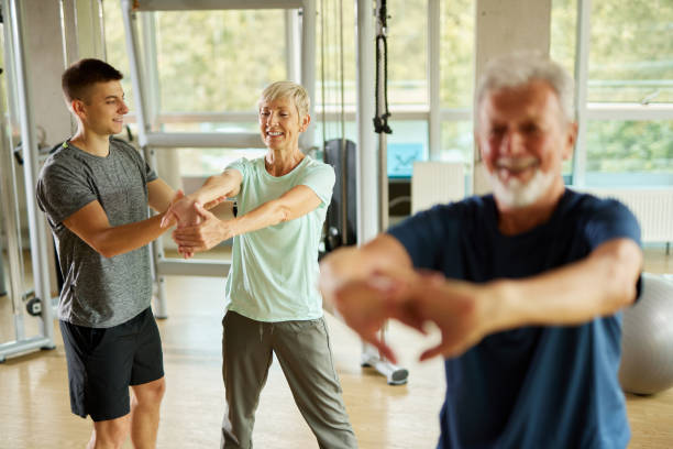 istock Senior couple doing stretching exercises with personal trainer at the gym 1425601855