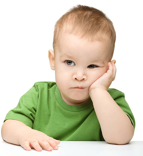 Pensive little boy support his head with hand stock photo