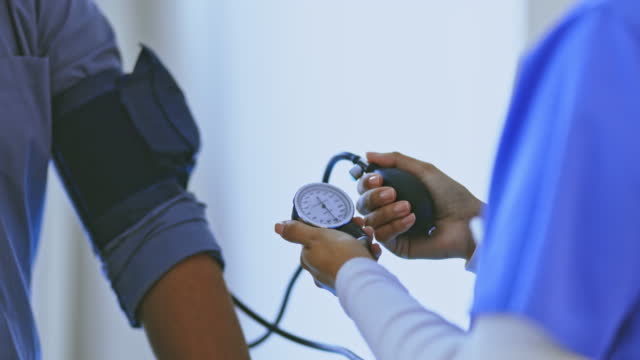 Blood pressure, hypertension and doctor check diabetes, healthcare consulting and patient service in clinic. Closeup nurse hands, measuring arm pulse and medicine test for healthy medical wellness