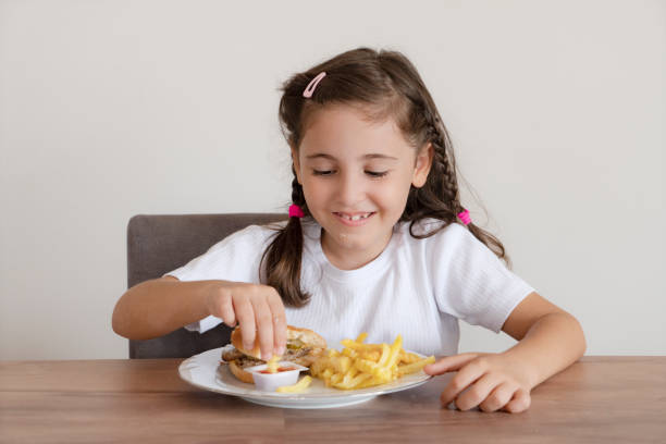 istock Little girl eating a big burger 1425604146