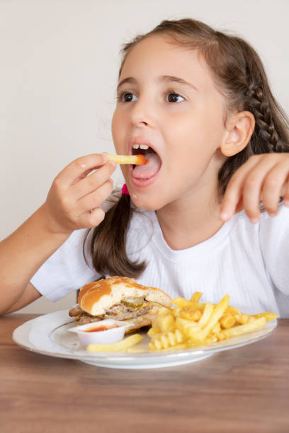 istock Little girl eating a big burger 1425604478