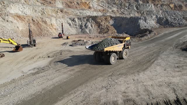 Aerial view of a mining truck is driving an iron ore mine loaded with ore.