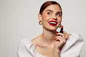 Beautiful emotional woman with bright make-up applying red lipstick