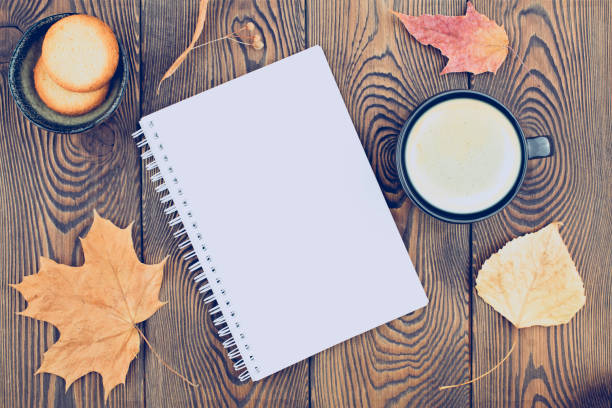 istock Autumn composition with an empty diary with spring, autumn dry leaves, a cup of coffee and cookies on a wooden background. Flat lay, copy space 1425612335