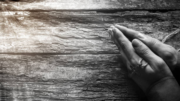istock man praying with a cross in his hands on a wooden background 1425614255