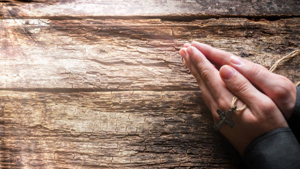 man praying with a cross in his hands on a wooden background man praying with a cross in his hands on a wooden background christian social union photos stock pictures, royalty-free photos & images