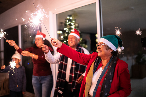 Senior woman with family celebrating christmas with sparklers at home