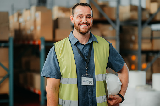 Factory or warehouse worker in a cargo plant happy about the shipping, export and delivery industry. Portrait of a young logistics or supply chain manager smiling about distribution