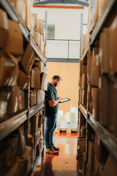 mitarbeiter der logistik-, lager- und versandfabrik mit tablet in der hand, der in der versand- oder frachtfabrik arbeitet. management, werks- oder lagerleiter supply chain industrie und lieferunternehmen - business ceo building activity business person stock-fotos und bilder