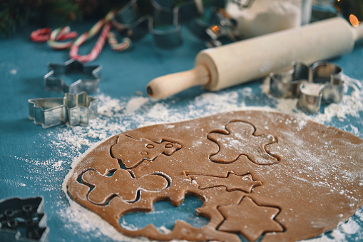 Christmas baking background with copy space for a greeting text, peace of dough rolled out for cooking Xmas gingerbreads, top down view