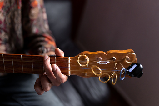 A Mexican musician is playing a chord with his jarana guitar checking the tuner. Concept of composing music.