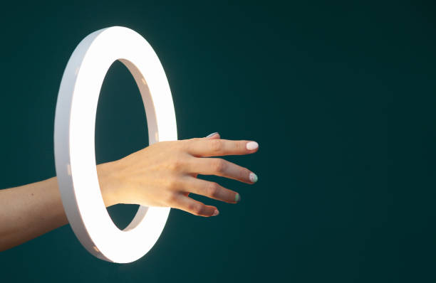 istock Woman's hand through a glowing circle ring lamp on a green background 1425624409