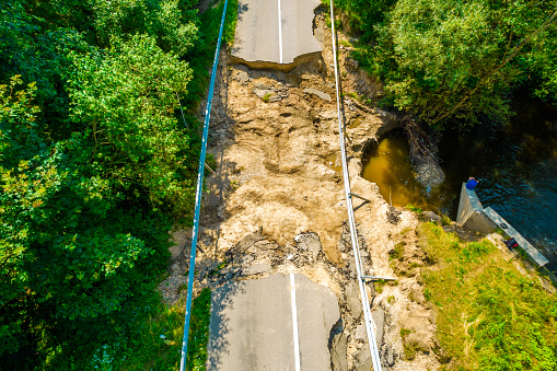 The asphalt road and bridge washed out and destroyed after the heavy rain and flood. Aerial photo