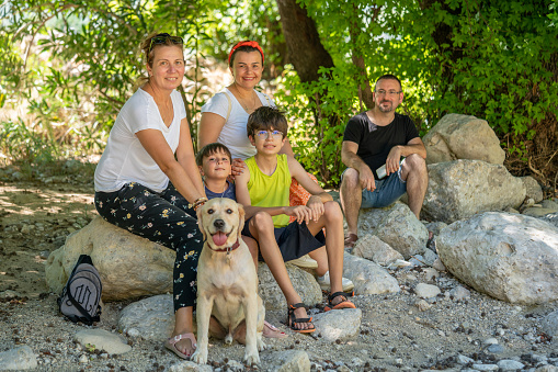Happy multi ethnic family with a dog relaxing in the nature.