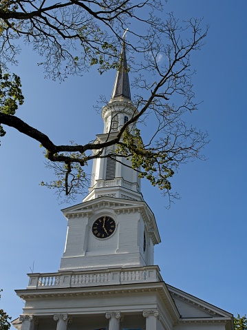 The steeple and exterior of the loyola alumni memorial chapel on the evergreen campus at Loyola University in Baltimore Maryland on a sunny blue sky day.