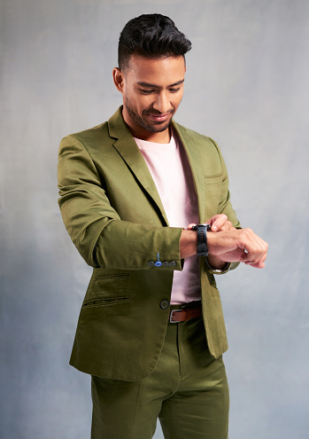 Watch time, fashion suit and businessman with luxury designer clothes, reading on smartwatch and happy with technology against grey mockup studio background. Rich, wealth and Asian man with clock