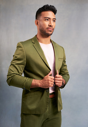 Fashion, stylish suit and model man in a studio posing for luxury clothing brand against a grey background. Elegant, smart casual and handsome gentlemen feeling confident and fashionable in green