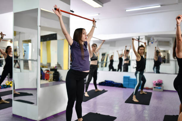 istock Female Athletes Using Sticks And Poles For Flexibility Exercises In Gym 1425646463