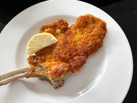 close-up of wiener schnitzel with lemon on white plate